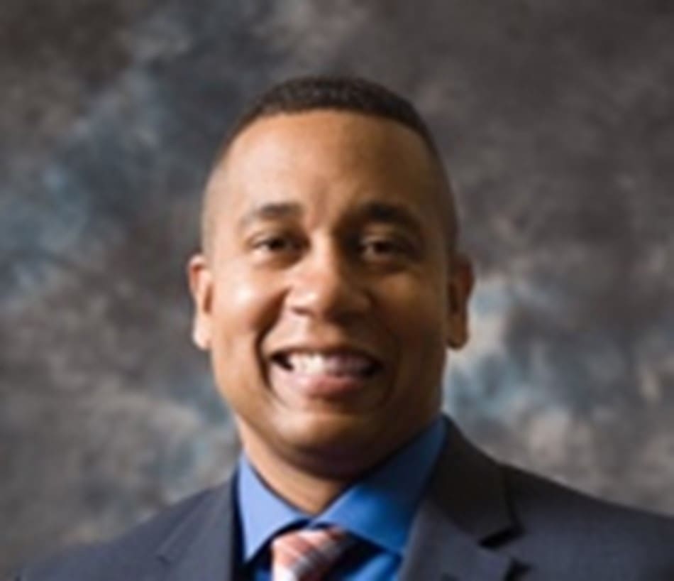 A man in a suit and tie smiling for the camera.